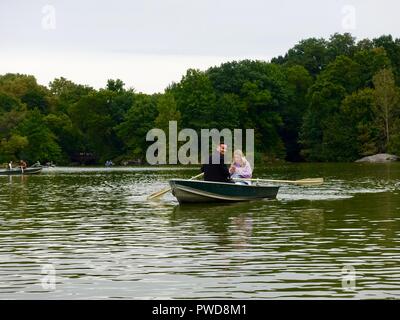 Couple in rowboat, man looking at camera, woman on her cell phone, lake in Central Park, New York, NY, USA. Stock Photo