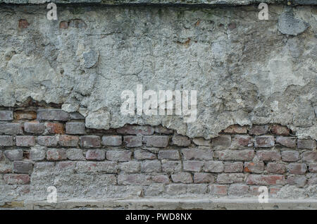 Old a masonry with red slightly broken bricks. Plaster are partly fallen. Some of bricks are missing. Stock Photo