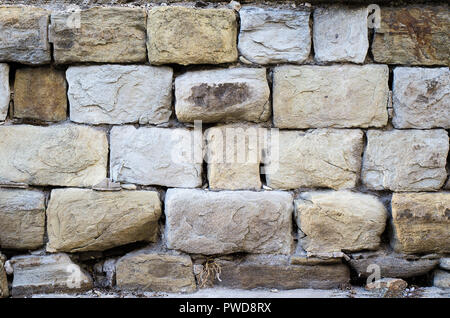 Massive a stone masonry with grey, light brown rectangular rocks. Erased adhesive mixture. Great weighing on its place hard, thick wall. Stock Photo