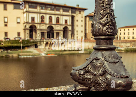 Beautiful details of the base of a streetlamp are in focus with the Uffizi on the other side of the Arno as backdrop. Stock Photo