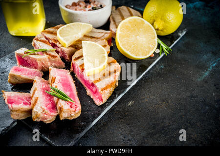 Grilled tuna fish steaks with lemon and spices, dark blue concrete background copy space top view Stock Photo
