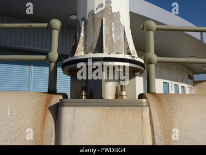 Fabricated and welded stainless steel wind turbine mounting fixed to concrete sea wall and supporting weathered metal mast in Cleveleys lancashire uk Stock Photo