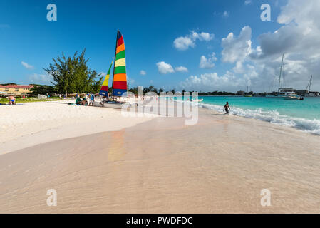 Bridgetown, Barbados - December 18, 2016: Brownes beach at ocean coast with people and colorful sail on a yacht at sunny day in Carlisle bay, Bridgeto Stock Photo