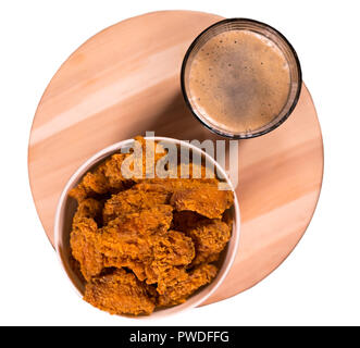 Deep fried crumbed chicken nuggets served in a takeaway tub with a pint of frothy beer viewed from above Stock Photo
