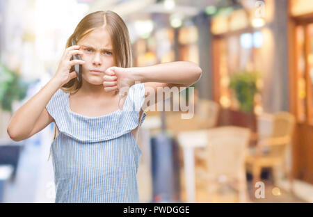 Young beautiful girl talking on the phone over isolated background with angry face, negative sign showing dislike with thumbs down, rejection concept Stock Photo