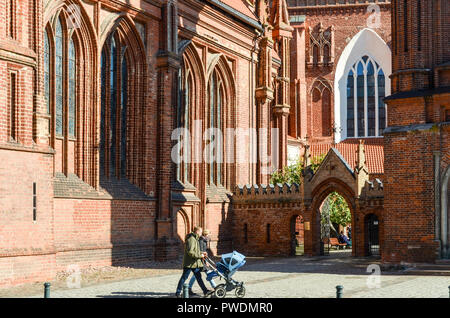 Couple with pram walking in front of the St. Francis of Assisi (Bernardine) Roman Catholic Church in Vilnius, Lithuania Stock Photo