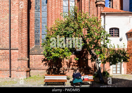 Woman sitting on a bench at the St. Francis of Assisi (Bernardine) Roman Catholic Church in Vilnius, Lithuania Stock Photo