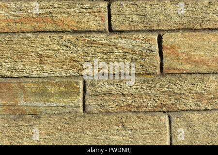 Rugged texture. Stone bricks rough texture. Background with soft colours, sunset light: orange, yellow, brown. Vertical and horizontal lines. Stock Photo