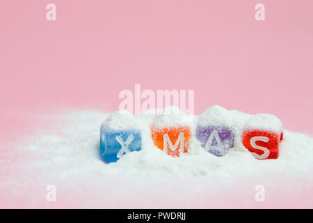 words merry christmas made of colorful letters blocks on white snow and pink background. Flat lay, top view - holidays, winter, christmas and new year Stock Photo