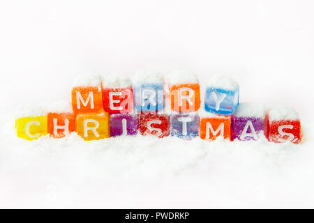 words merry christmas made of colorful letters blocks on white snow background. Flat lay, top view - holidays, winter, christmas and new year celebrat Stock Photo