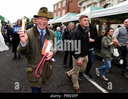 Bournemouth, UK. 15th Oct 2018. Nigel Farage MEP visits Bournemouth's Christchurch Market during the Leave Means Leave Brexit tour, UK. A stall holder gifts Nigel a leash and collar to 'control Theresa May' Credit: Finnbarr Webster/Alamy Live News Stock Photo