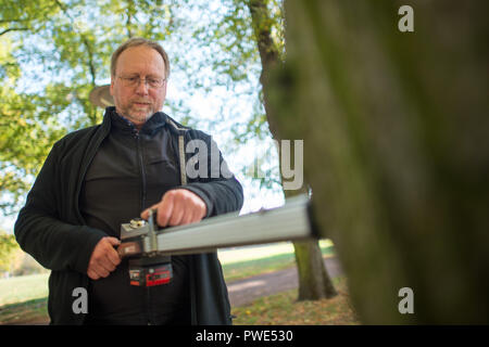 11 October 2018, Saxony-Anhalt, Magdeburg: Jörg Vollbrecht, expert for traffic safety, tree value determination and tree register of the company Klaus und Partner, checks the strength of the interior of a tree in the Rotehornpark with a drilling resistance meter. (to "Increased tree mortality in Saxony-Anhalt feared after drought-summer" of 16.10.2018) Photo: Klaus-Dietmar Gabbert/dpa-Zentralbild/ZB Stock Photo