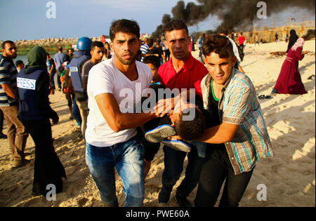 October 15, 2018 - Dozens of Palestinian protesters are injured during clashes with the Israeli army on a beach in northwestern Gaza, close to the border with Israel, on 15th October 2018. Injured protesters were rescued by paramedics after being hit by Israeli live gunfire and being asphyxiated by tear gas. Hundreds of demonstrators had gathered on the beach near Beit Lahiya to demand the lift of the Israeli blockade on Gaza, which Israel has imposed since 2007, as Hamas took over power in the Strip, and which has been strangling the Palestinian enclave and causing a humanitarian crisis for t Stock Photo