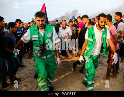 October 15, 2018 - Dozens of Palestinian protesters are injured during clashes with the Israeli army on a beach in northwestern Gaza, close to the border with Israel, on 15th October 2018. Injured protesters were rescued by paramedics after being hit by Israeli live gunfire and being asphyxiated by tear gas. Hundreds of demonstrators had gathered on the beach near Beit Lahiya to demand the lift of the Israeli blockade on Gaza, which Israel has imposed since 2007, as Hamas took over power in the Strip, and which has been strangling the Palestinian enclave and causing a humanitarian crisis for t Stock Photo