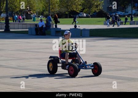 Children ride in the park on cars with pedals. Admiral Serebryakov Square. Childrens leisure. Stock Photo