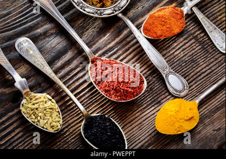 Assortment of spices in vintage spoons on wooden background Stock Photo