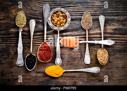 Assortment of spices in vintage spoons on wooden background Stock Photo
