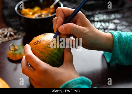 Image of hands of man drawing on pumpkin face Stock Photo