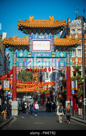 LONDON - OCTOBER 10, 2018: Decorative red lanterns hang above the street beyond a decorative gate erected in 2016 to mark the entrance to Chinatown. Stock Photo