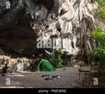 Man sitting near the orange tent on the beach Stock Photo