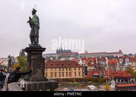 Tourists touching Bronze Wishing convex statue, bronze plaque of John of Nepomuk,  In Charles Bridge, Karlův most, Prague, Czech Republic. Stock Photo