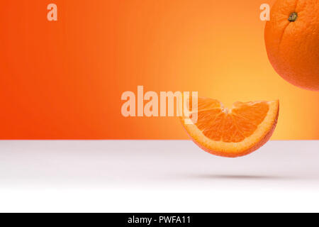 Floating oranges isolated on an orange and white background with space for text Stock Photo