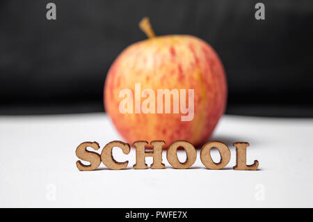 The word School in front of an apple isolated on black background Stock Photo