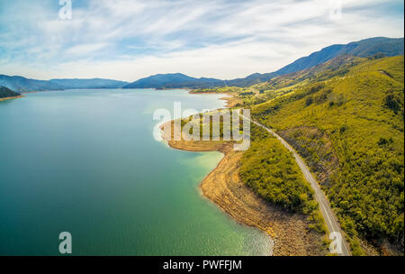 Rural highway winding along shore of Blowering Reservoir - aerial panorama Stock Photo