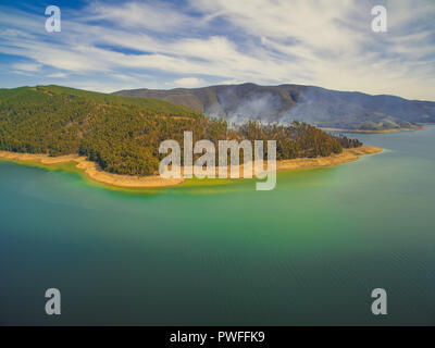 Aerial view of forest fire on shores of Blowering reservoir lake Stock Photo
