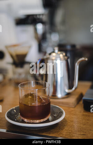 Iced drip coffee with ice ball in glass with blur coffee bar scene Stock Photo