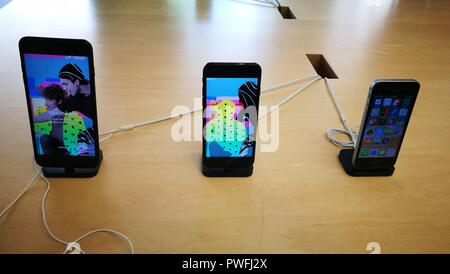Three apple iPhone, 2018 editions on display with light wooden background. Stock Photo