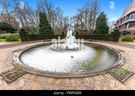 Cold and frozen fountain water in the middle of the pond and a beautiful garden Stock Photo