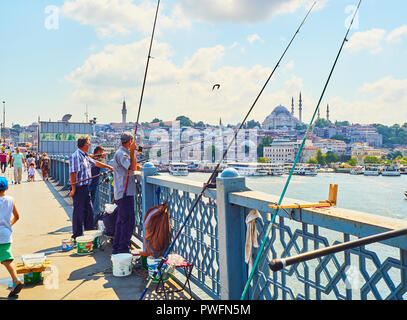 Citizens on the Galata bridge fishing in the mouth of the Golden Horn Bay, and a view of the Eminonu district skyline in the background. Istanbul. Stock Photo