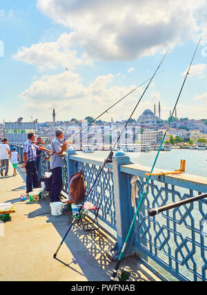 Citizens on the Galata bridge fishing in the mouth of the Golden Horn Bay, and a view of the Eminonu district skyline in the background. Istanbul. Stock Photo