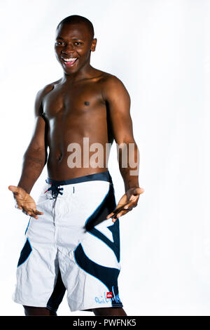 African young male wearing shorts and no shirt laughing and gesturing. On his arms are prison tattoos Stock Photo