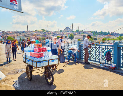 Delivery boy transporting drinks and citizens fishing on the Galata bridge with a view of the Eminonu district skyline in the background. Istanbul. Stock Photo