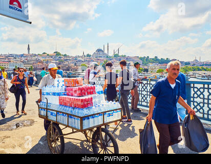 Delivery boy transporting drinks and citizens fishing on the Galata bridge with a view of the Eminonu district skyline in the background. Istanbul. Stock Photo