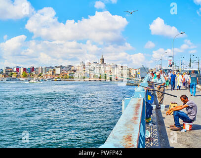 Citizens on the Galata bridge fishing in the mouth of the Golden Horn Bay with a view of the Karakoy district skyline in the background. Istanbul. Stock Photo