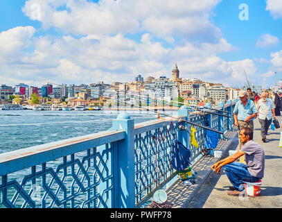 Citizens on the Galata bridge fishing in the mouth of the Golden Horn Bay with a view of the Karakoy district skyline in the background. Istanbul. Stock Photo