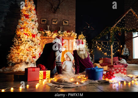 Happy family with a baby in a Santa Claus hat in a Christmas room in Christmas day. Stock Photo