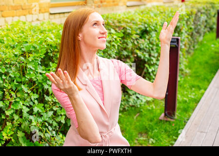 Beautiful young girl sitting on a wooden bench in the open Rejoices. Sunny day green bushes lifestyle Selective focus copy space Stock Photo