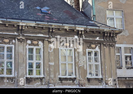 Weathered old apartment houses with tall multi pane windows and pain peeling off from exterior walls. Stock Photo