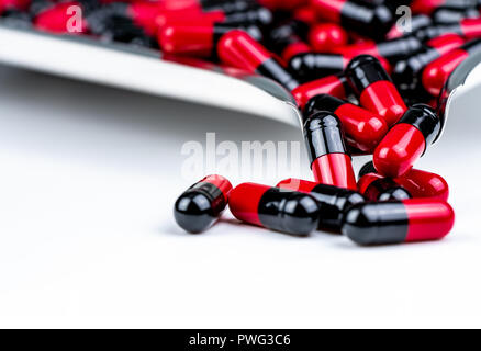 Selective focus of red and black capsule pills on stainless steel drug tray. Antibiotics drug resistance. Global healthcare. Antimicrobial capsule pil Stock Photo