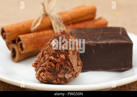 Chocolate truffle and chocolate candy on white plate with cinnamon. Selective focus on truffle Stock Photo