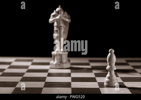 Classic white bishop and the same chess piece in the form of medieval figure on the background. Selective focus on classic piece Stock Photo