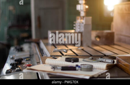 A private workshop for working with metal parts, in the background a drilling machine drills a hole in the pulley, on the table lie measuring instrume Stock Photo