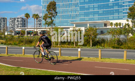 Cyclist riding bicycle cycling past Crown Towers luxury hotel in Burswood Perth Western Australia Stock Photo