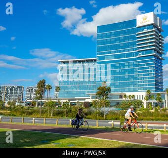 Cyclists riding bicycles cycling past Crown Towers luxury hotel in Burswood Perth Western Australia. Stock Photo