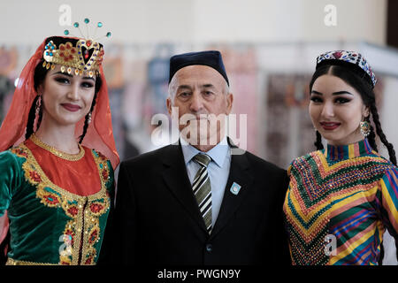 An elderly Uzbek man posing with young women wearing traditional garment in the city of Tashkent capital of Uzbekistan Stock Photo