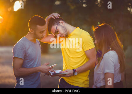 Three friends are outdoors argueing about directions in the park Stock Photo